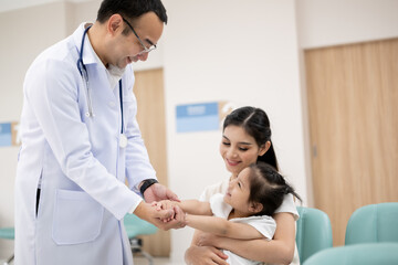 The doctor held the young patient's hand, and the mother smiled and encouraged her.