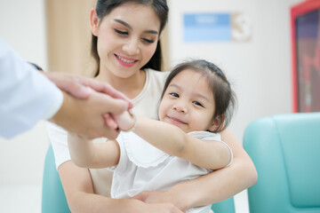 Fototapeta premium The doctor held the young patient's hand, and the mother smiled and encouraged her.
