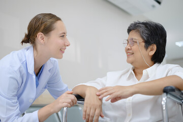 Obraz premium Young female doctor health examining to an old female patient and her family sitting in a wheelchair.