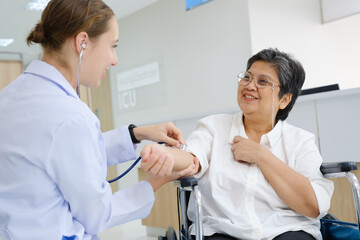 Fototapeta premium Young female doctor health examining to an old female patient and her family sitting in a wheelchair.