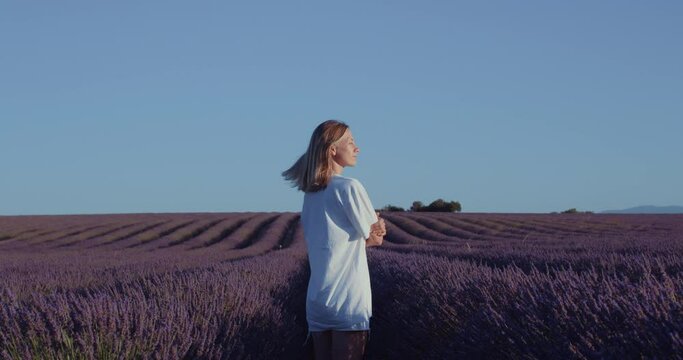 Dreamy girl in lavender fields at sunrise. Freedom and peace of nature. Outdoor lover. Female role model or blogger. Gentle breeze rustles her hair. Power of silence and mindfulness. 