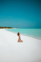 Young Woman In Bikini Enjoying The Sun On The White Sand Beach In Maldives