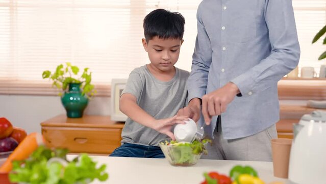 4K, Close-up handsome boy with chubby cheeks, fruit salad stand big plate with dad for mom eat in her spare time, on father-son holiday next him is father who teaches helps his son.