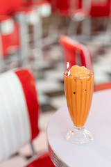 Iced Thai tea in glass on white table in vintage cafe