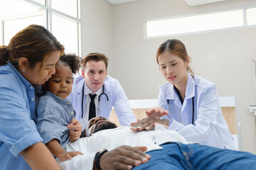 Fototapeta premium Doctors examine a black patient who has had an accident with a broken leg accompanied by his wife and child.