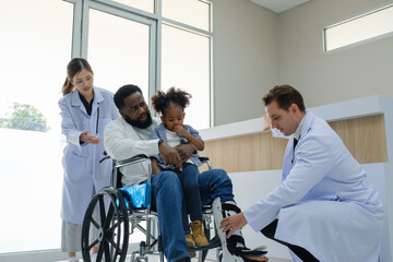 Obraz premium Doctors examine a black patient who has had an accident with a broken leg accompanied by his wife and child.