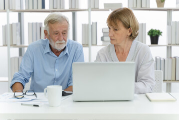 Mature couple looking at finance document and data on laptop computer and having a money problems