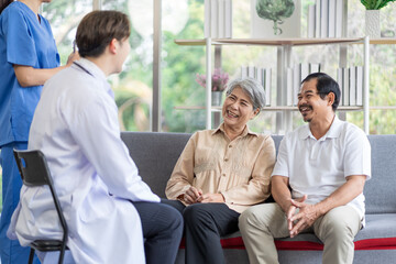 Fototapeta premium Asian couple Elderly men and women sit on sofas having fun and having fun talking with doctors who come to check their health at home.