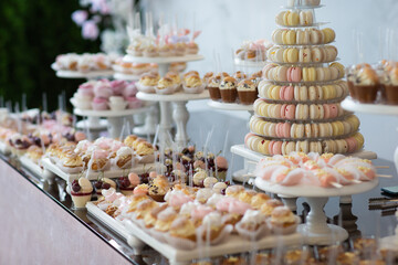 Candy bar on wedding. Candy bar standing of festive table with deserts, cupcakes and macarons. 