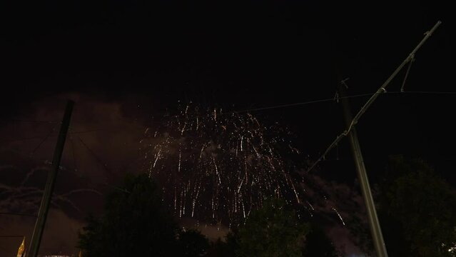 Utility poles with electrical cables outdoors at background of fireworks. Night show in urban city in darkness