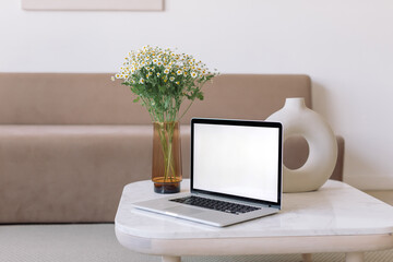 Laptop computer with blank screen mockup on marble table in minimalistic Scandinavian interior. Business, marketing, portfolio showcase mockup.