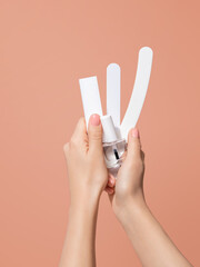 Female hands holding manicure tools: a transparent nail polish and assorted nail files. Image demonstrating professional salon service and manicure artist occupation. Home self care and treatment.
