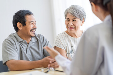 Obraz premium Asian seniors who are healthy, in a good mood, smiling, talking with financial or life insurance staff to take care of life after retirement.