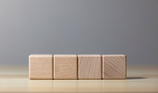 Four wooden blocks on wooden table with gray background