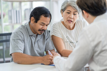 Fototapeta premium Asian seniors who are healthy, in a good mood, smiling, talking with financial or life insurance staff to take care of life after retirement.