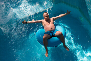 Adult man rides on an inflatable circle cheesecake water park.
