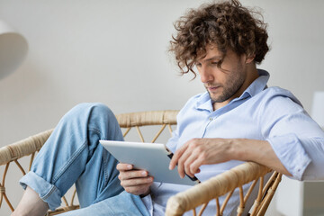 Young man wearing casual clothes smiling with laptop sitting on sofa
