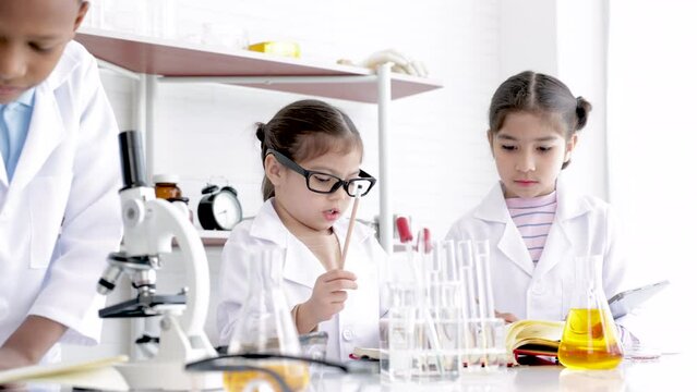 Primary school kids education in science laboratory classroom concept, students in gown uniform research or discover experiments in Chemistry lab, children having fun and scientific equipment and tube