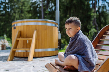 Little boy resting at deck chair after a hot tub.