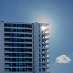 Modern apartment building with sun on blue sky background. Real estate concept.