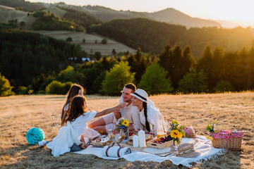 Happy family with children having picnic in nature.