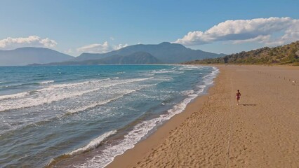 arial drone view Young women exercising with outdoor running with sea and mountain background. When sun raises in Turkey in summer, Concept healthy running and outdoor exercise, Tracking dolly shot
