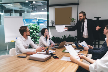 Attentive colleagues listening to serious boss during business plan discussion in office