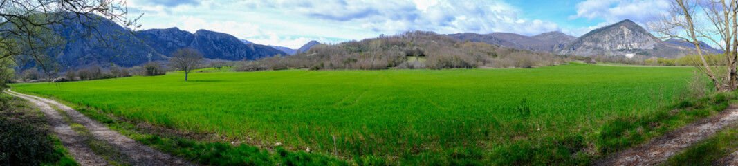 Fototapeta premium Panoramic view of a green field with mountains in the background, Rocchetta al Volturno, Molise