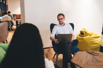 Content employee speaking with unrecognizable lady in workplace