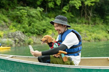 カヤックで飼い犬と一緒に写真を撮る男性