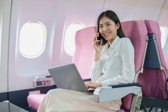Asian business woman passenger sitting on business class luxury plane while working using smart phone mobile talking or video conference and travel concept