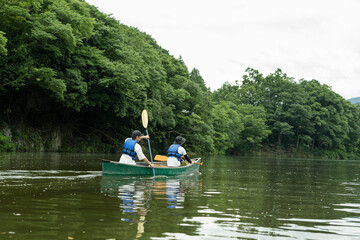 Fototapeta na wymiar 友人と一緒にカヤックで川下りを楽しむ男性