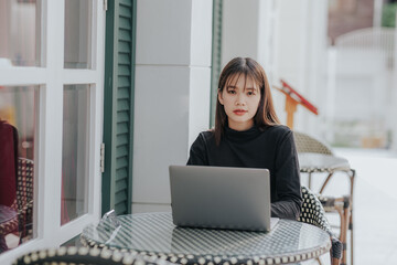 Beautiful Asian black shirt woman using laptop in coffee shop.