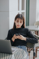 Beautiful Asian black shirt woman using laptop in coffee shop.