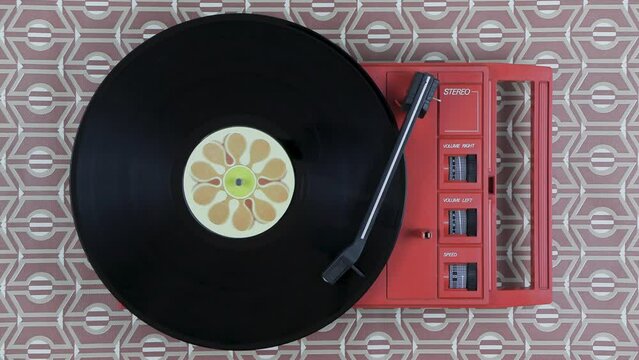 Top view of a spinning vintage cute orange record player on a retro background
