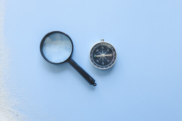 Fototapeta na wymiar Magnifier, compasses and seashells on light background