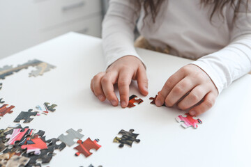 Fototapeta premium Hands of a child doing a puzzle at table