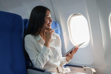 Asian attractive business woman passenger sitting on business class luxury plane while tablet computer while travel concept