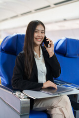 Asian business woman passenger sitting on business class luxury plane while working using smartphone mobile talking and use laptop computer with simulated space using on board wireless connection