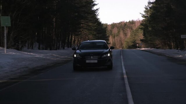 black car driving on the road in sunny weather, early spring, slow motion