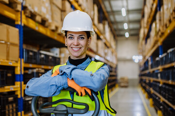 Portrait of warehouse female worker in reflective vest with a pallet truck.