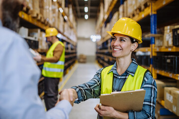 Manager shaking hands with employers in warehouse.