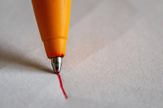 penna di colore rosso che traccia una riga su un foglio bianco
