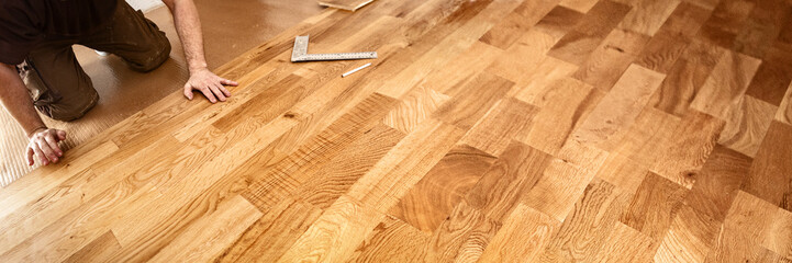 Craftsman laying oak parquet with a click system, panorama - 588401912
