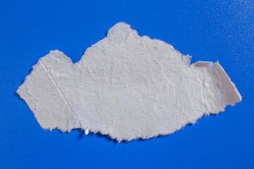 Ripped white paper piece on an isolated blue background. Design element.