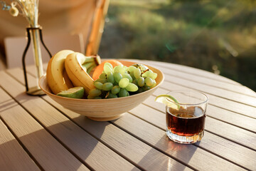 Glass of cocktail with rum and cola is standing on the table outside on nature background