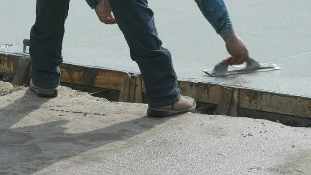 workman smoothing concrete on a newly poured street
