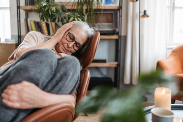 Obraz premium Sad senior woman sitting in her livingroom.