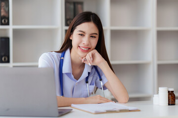 Smiling Happy and Beautiful Doctor working on laptop at clinic, health care, medical, healthy concept