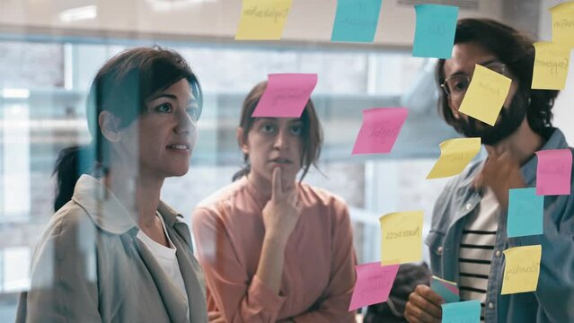 Team of creative professionals of modern company using sticky notes brainstorming ideas in the office 